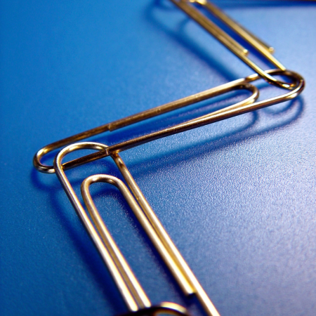 Linked paperclips forming a chain on a blue surface, symbolizing unity, strength, and the paperclip as resistance.